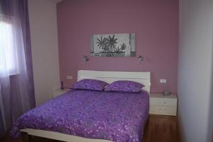 um quarto com uma cama roxa com lençóis roxos em Apartments with a parking space Razanj, Rogoznica - 22062 em Razanj