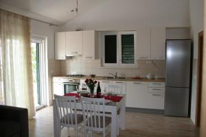 uma cozinha com armários brancos e uma mesa com cadeiras em Apartments with a parking space Razanj, Rogoznica - 22062 em Razanj