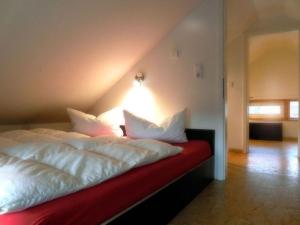 uma cama com lençóis brancos e almofadas em Lovely apartment in Immenstadt em Zierow