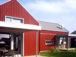 a red house with a white roof and a patio at Lovely apartment in Immenstadt in Zierow