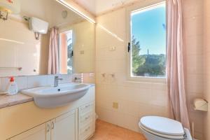 a bathroom with a sink and a toilet and a window at Villetta Norsi in Capoliveri
