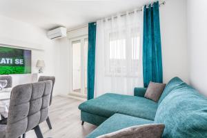 uma sala de estar com um sofá azul e cadeiras em Apartments with a parking space Split - 22452 em Split