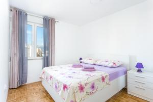 a white bedroom with a bed and a window at Apartments with a parking space Split - 22452 in Split