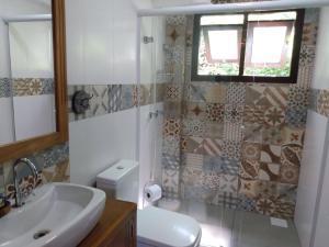 a bathroom with a sink and a toilet and a window at Pousada Vila Guyrá in Florianópolis
