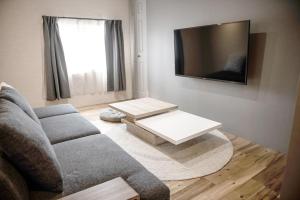 Il comprend un salon doté d'un canapé et d'une télévision à écran plat. dans l'établissement Sauna Villa Yoichi / 4 bed room with private sauna, à Kurokawamachi
