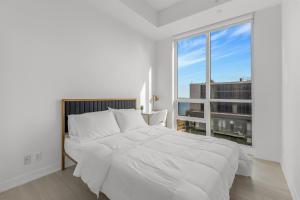 een slaapkamer met een wit bed en een groot raam bij *Luxury 2BR-2BA, High Floor, Unobstructed Lake View* in Toronto
