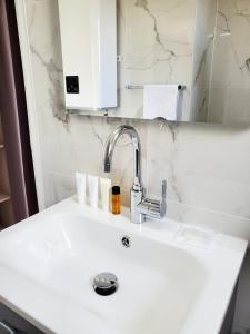 een witte wastafel in een badkamer met een spiegel bij Le Loft de L’Écluse / F2 cosy au bord de l'eau in Pontoise