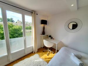 een slaapkamer met een bed, een bureau en een raam bij Le Loft de L’Écluse / F2 cosy au bord de l'eau in Pontoise
