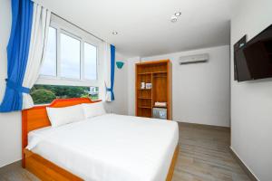 1 dormitorio con cama blanca y ventana en Light House Phú Quốc en Phu Quoc