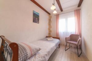 a bedroom with a bed and a chair and a window at Family friendly house with a swimming pool Veliki Brocanac, Zagora - 22666 in Klis