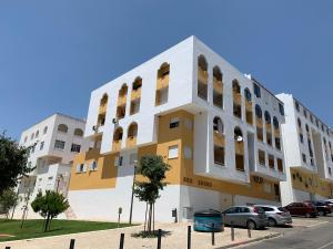 a building with cars parked in front of it at Quarteira Paul Harris Apartment in Quarteira