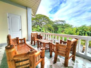 a porch with wooden chairs and a table on a balcony at Golda Coast Resort - Oslob in Oslob