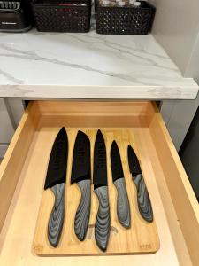a row of four knives on a wooden cutting board at Luxury Urban Oasis -10 Mins to NRG, Med Ctr & DT! in Houston