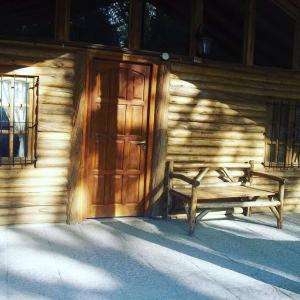 a wooden door of a building with a bench next to it at Cabañas Troncos Del Salto in Potrerillos