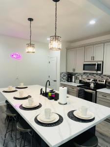 a kitchen with white cabinets and a large island with dishes on it at HTX Urban Oasis -Mins to Downtown, NRG, & Med Ctr! in Houston