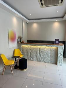 a lobby with two yellow chairs and a bar at Swing & Pillows - KL Kuchai Lama formerly known as Sunrise Inn in Kuala Lumpur