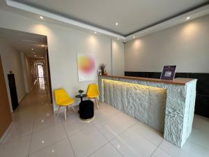 a lobby with two yellow chairs and a counter at Swing & Pillows - KL Kuchai Lama formerly known as Sunrise Inn in Kuala Lumpur