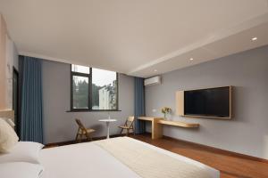 um quarto com uma cama e uma televisão de ecrã plano em Anlan Hotel Shangrao Wuyuan Cultural Plaza em Wuyuan