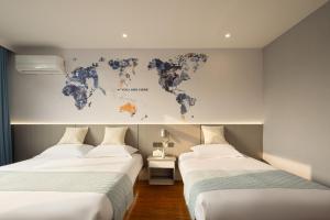 duas camas num quarto com um mapa do mundo na parede em Anlan Hotel Shangrao Wuyuan Cultural Plaza em Wuyuan
