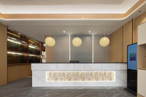 a lobby with a reception counter with three lights at Anlan Hotel Shangrao Wuyuan Cultural Plaza in Wuyuan