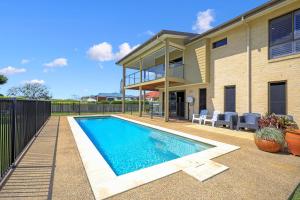 a swimming pool in front of a house at Nudibranch House in Bargara