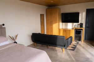 a bedroom with a black couch and a flat screen tv at MiLu in El Porvenir