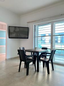 een eetkamer met een tafel en stoelen en een tv bij Guakmaya hostel in Cartagena