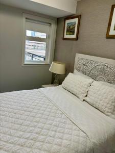 1 dormitorio con cama blanca y ventana en Lovely lake view apartment downtown Calgary one bedroom fully furnished, en Calgary