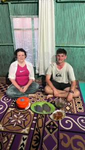 mężczyzna i kobieta siedzący na podłodze w obiekcie Jhuna Komodo Homestay w mieście Komodo