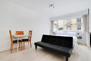 巴黎的住宿－Appartement Alesia，白色卧室配有黑色沙发和桌子
