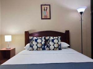 a bedroom with a bed with a pillow and a lamp at Casa Cacique Liberia - No Garage in Liberia