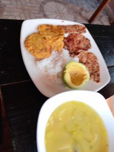 a plate of food with rice and meat and a pickle at Hostal Piedra del Ocaso in Manizales