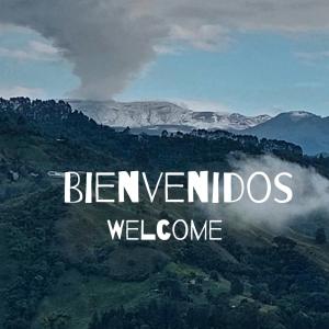 a sign that reads benvimos welcome with a mountain in the background at Hostal Piedra del Ocaso in Manizales