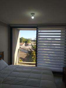 sypialnia z łóżkiem i dużym oknem w obiekcie Departamento Centro Plaza 403 w mieście Pitrufquén