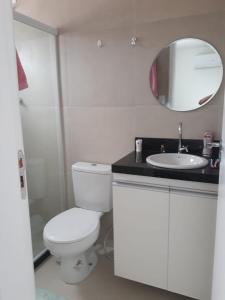 a bathroom with a toilet and a sink and a mirror at Praça 10 in Porto De Galinhas