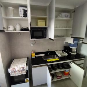 a small kitchen with a sink and a microwave at Praça 10 in Porto De Galinhas