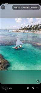 a boat with a sail in the water at Praça 10 in Porto De Galinhas