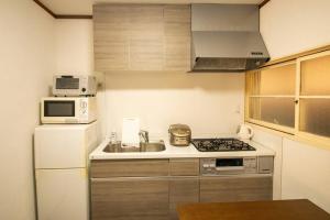 een kleine keuken met een fornuis en een magnetron bij BRUCE GUESTHOUSE KIX in Osaka