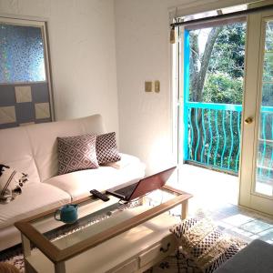 ゴンドラヴィラ イン熱海 في أتامي: غرفة معيشة مع أريكة وطاولة زجاجية