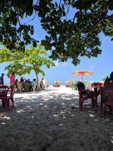 um grupo de mesas e cadeiras com guarda-sóis na praia em Casa aconchegante próxima a Praia de Jaguaribe em Itamaracá