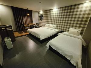 No. 25 Hotel Myeongji Oceanc City Business في بوسان: غرفة فندقية بسريرين وطاولة