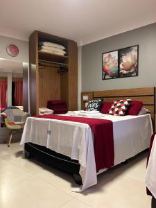 Schlafzimmer mit einem großen Bett mit roter und weißer Bettwäsche in der Unterkunft Araras Apart Service I in Caldas Novas