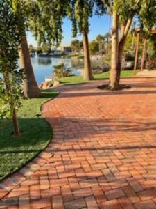a brick walkway with trees and a body of water at Water Front Sweet Home in Mesa