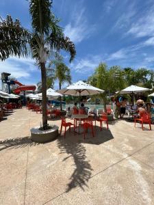 um grupo de mesas e cadeiras com guarda-sóis num resort em Araras Apart Service I em Caldas Novas