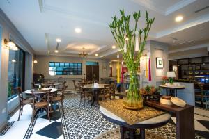un restaurante con mesas y sillas y un jarrón con flores en Somerset Hotel, en Miri