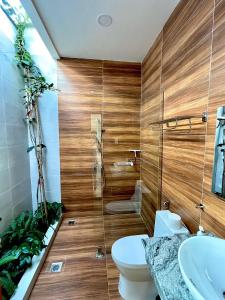 a bathroom with wooden walls and a toilet and a sink at Sông Mê Home in Vĩnh Long