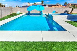 a swimming pool with an umbrella in the grass at HOUSE VEGAS in Las Vegas
