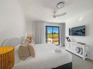 a white bedroom with a bed and a window at Florette's Retreat in Pokolbin