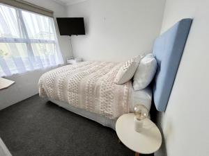 a bedroom with a bed with a blue headboard and a table at House of Somer in Matamata