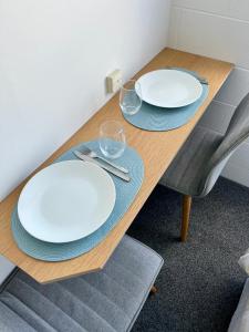 two white plates and glasses on a wooden table at House of Somer in Matamata +14 photos